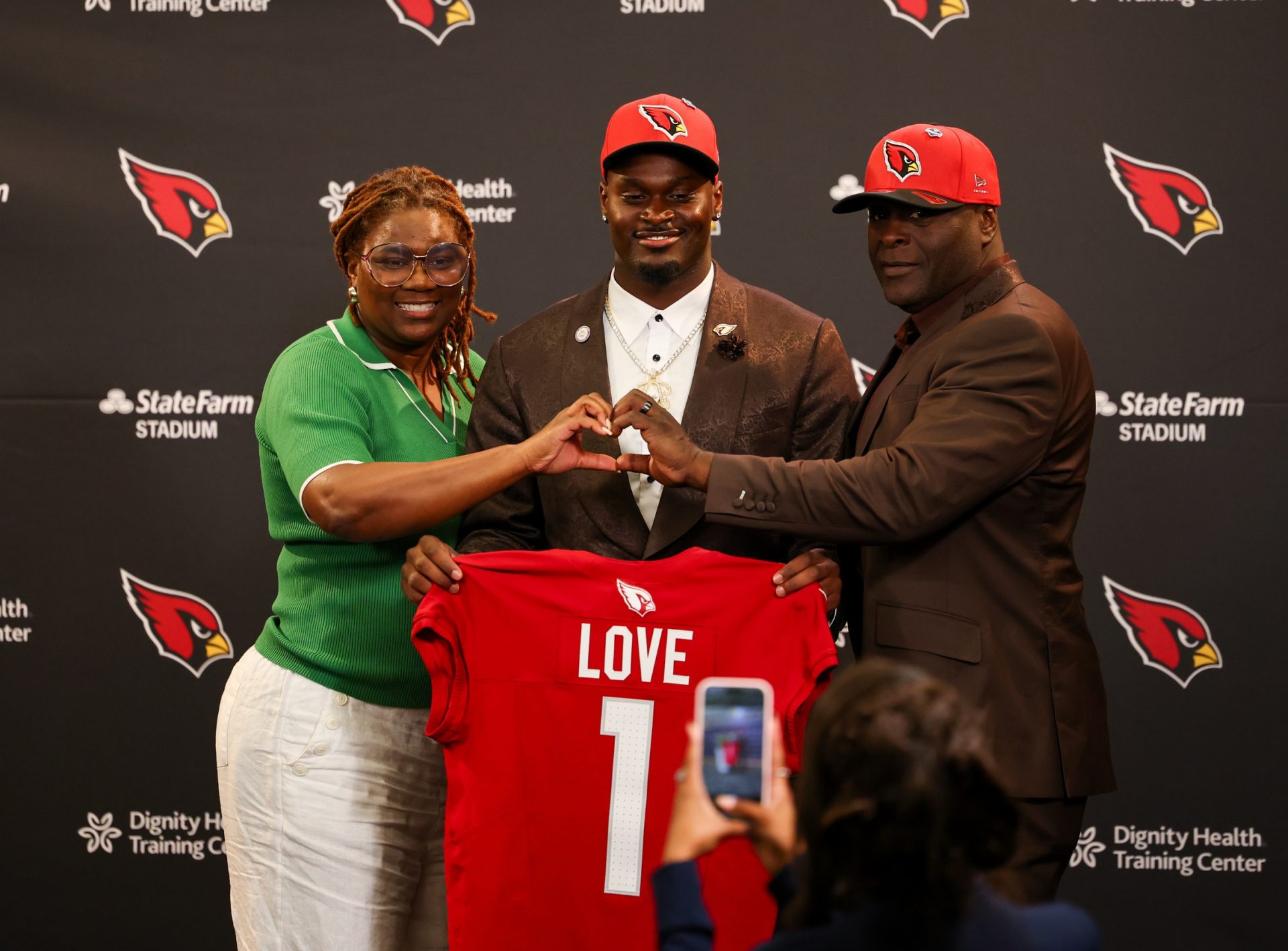 Arizona Cardinals first-round draft pick Jeremiyah Love poses with his jersey and his parents during a press conference at Dignity Health Arizona Cardinals Training Center.  Source: Imagn