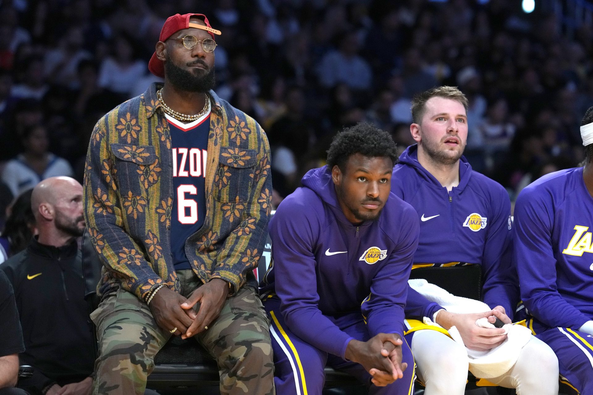 Los Angeles Lakers forward LeBron James (left), guard Bronny James (center) and guard Luka Doncic watch from the bench in the first half against the Minnesota Timberwolves at Crypto.com Arena.