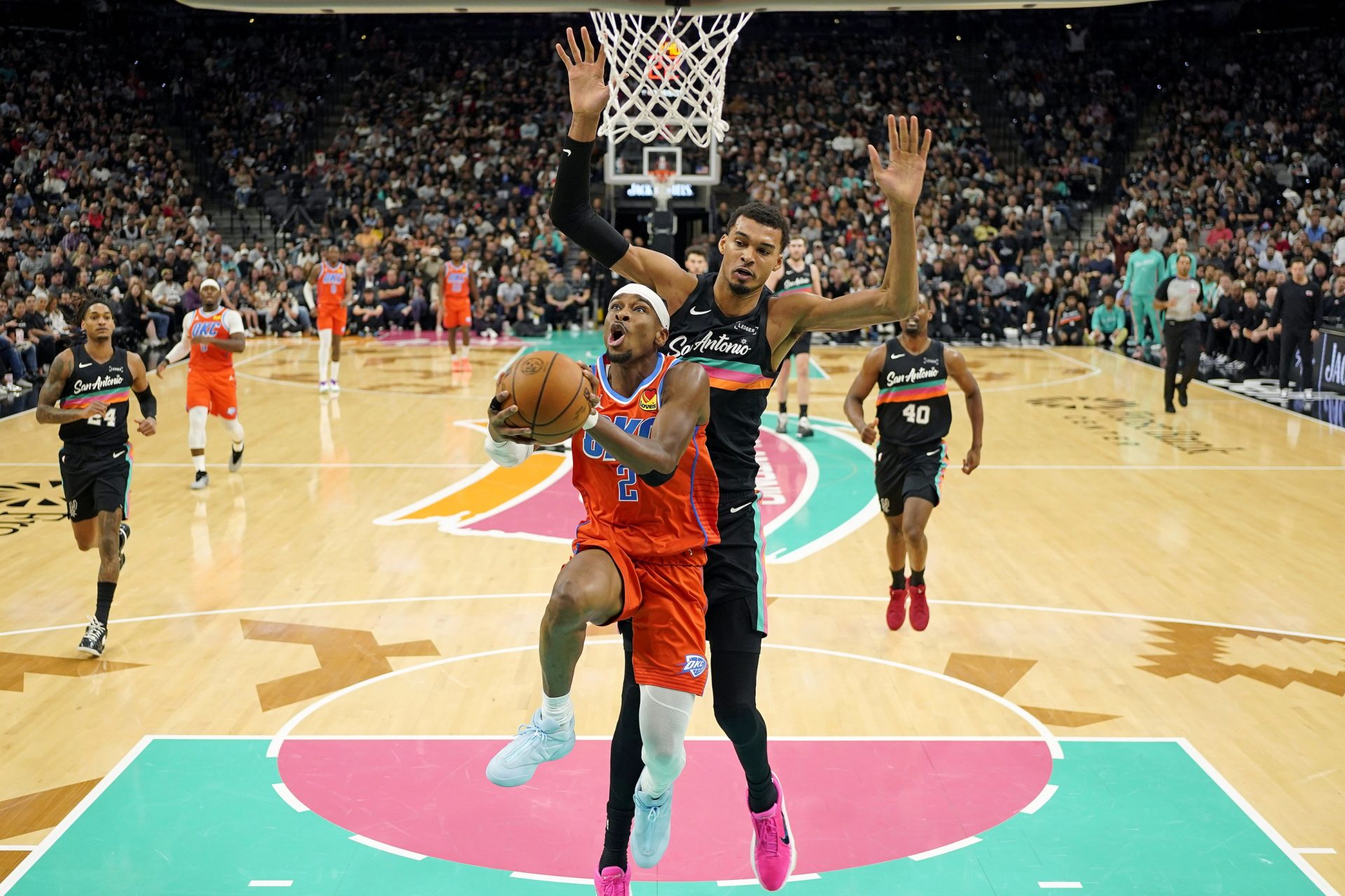 Oklahoma City Thunder guard Shai Gilgeous-Alexander (2) drives to the basket past San Antonio Spurs forward Victor Wembanyama (1) during the first half at Frost Bank Center.