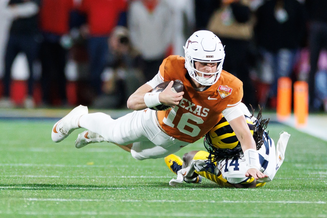 Texas Longhorns quarterback Arch Manning (16) reaches with the ball for a first down while Michigan Wolverines defensive back Jordan Young (14) attempts to tackle during the second half at Camping World Stadium.