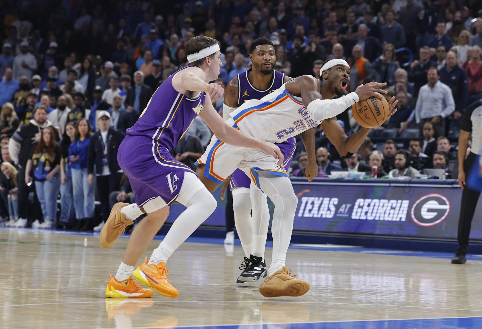 Oklahoma City Thunder guard Shai Gilgeous-Alexander (2) drives between Los Angeles Lakers guard Austin Reaves (15) and guard Marcus Smart (36) during the second quarter at Paycom Center.