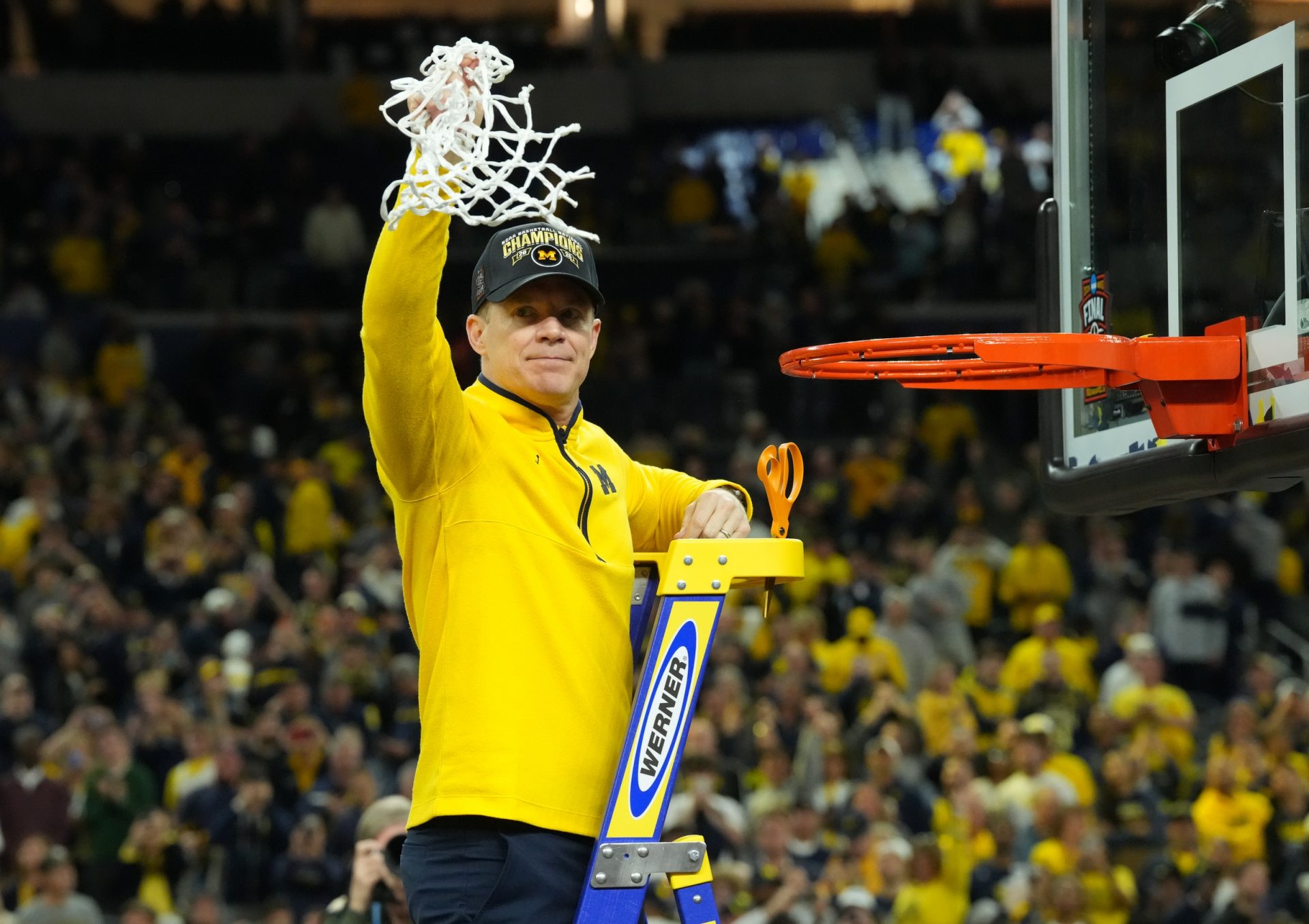 Michigan Wolverines head coach Dusty May cuts down the net after defeating the Connecticut Huskies in the national championship of the Final Four of the men's 2026 NCAA Tournament at Lucas Oil Stadium.