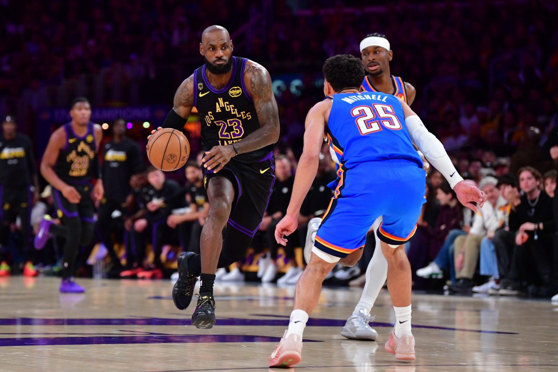 Los Angeles Lakers forward LeBron James (23) moves the ball against Oklahoma City Thunder guard Shai Gilgeous-Alexander (2) and guard Ajay Mitchell (25) during the first half in game four of the second round of the 2026 NBA Playoffs at Crypto.com Arena.