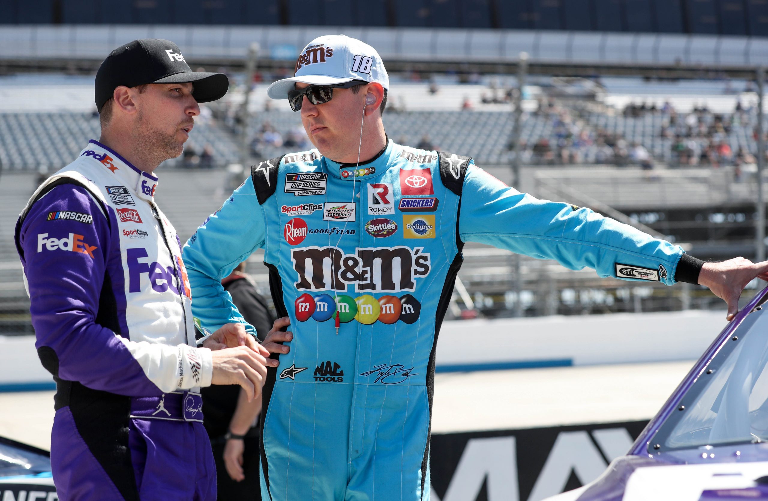 NASCAR Cup Series driver Kyle Busch (right) talks with driver Denny Hamlin (left) on pit road during qualifying for the DuraMAX Drydene 400 at Dover Motor Speedway.