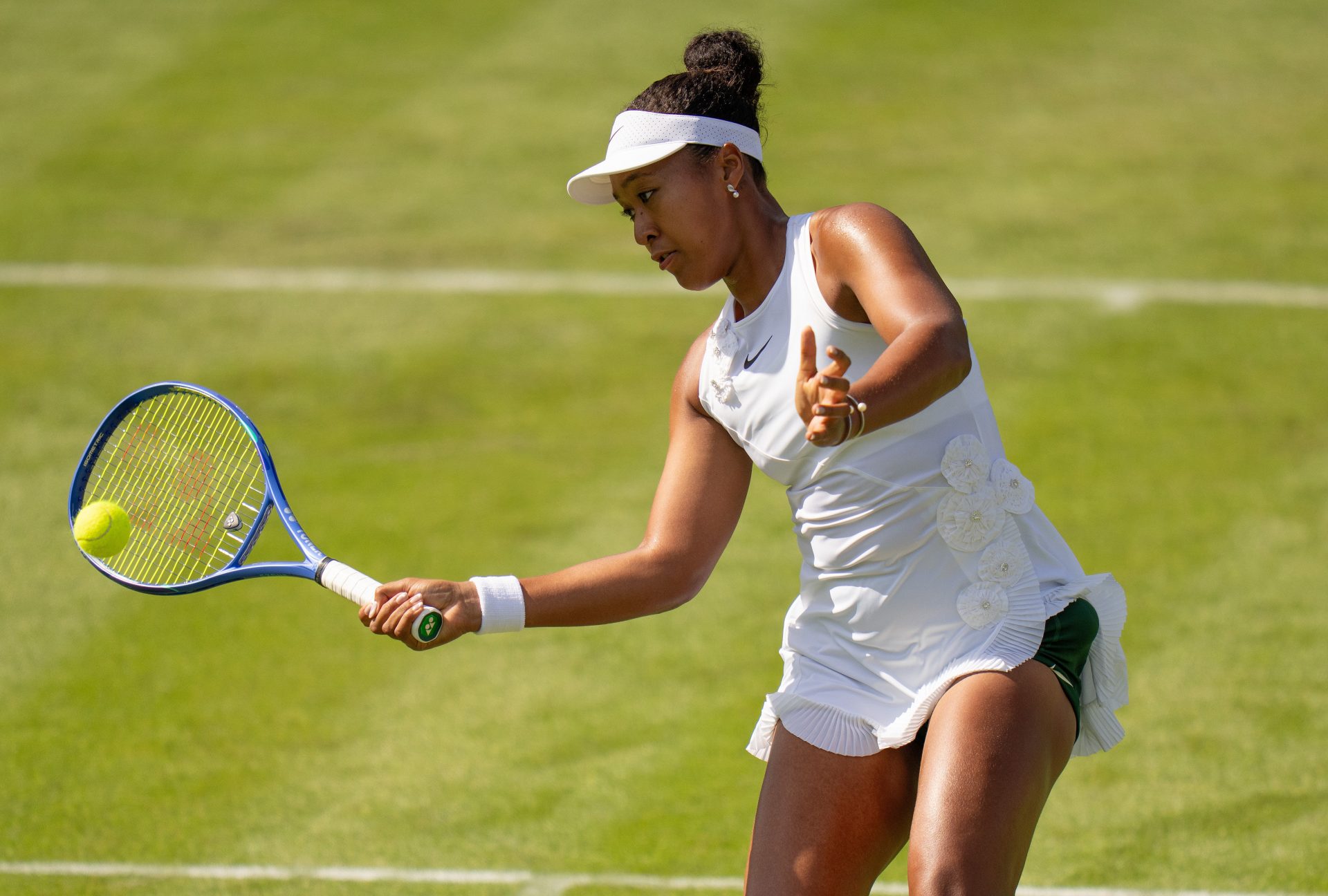 Naomi Osaka of Japan returns a shot during her match against Elsa Jacquemot of France on day one at All England Lawn Tennis and Croquet Club.