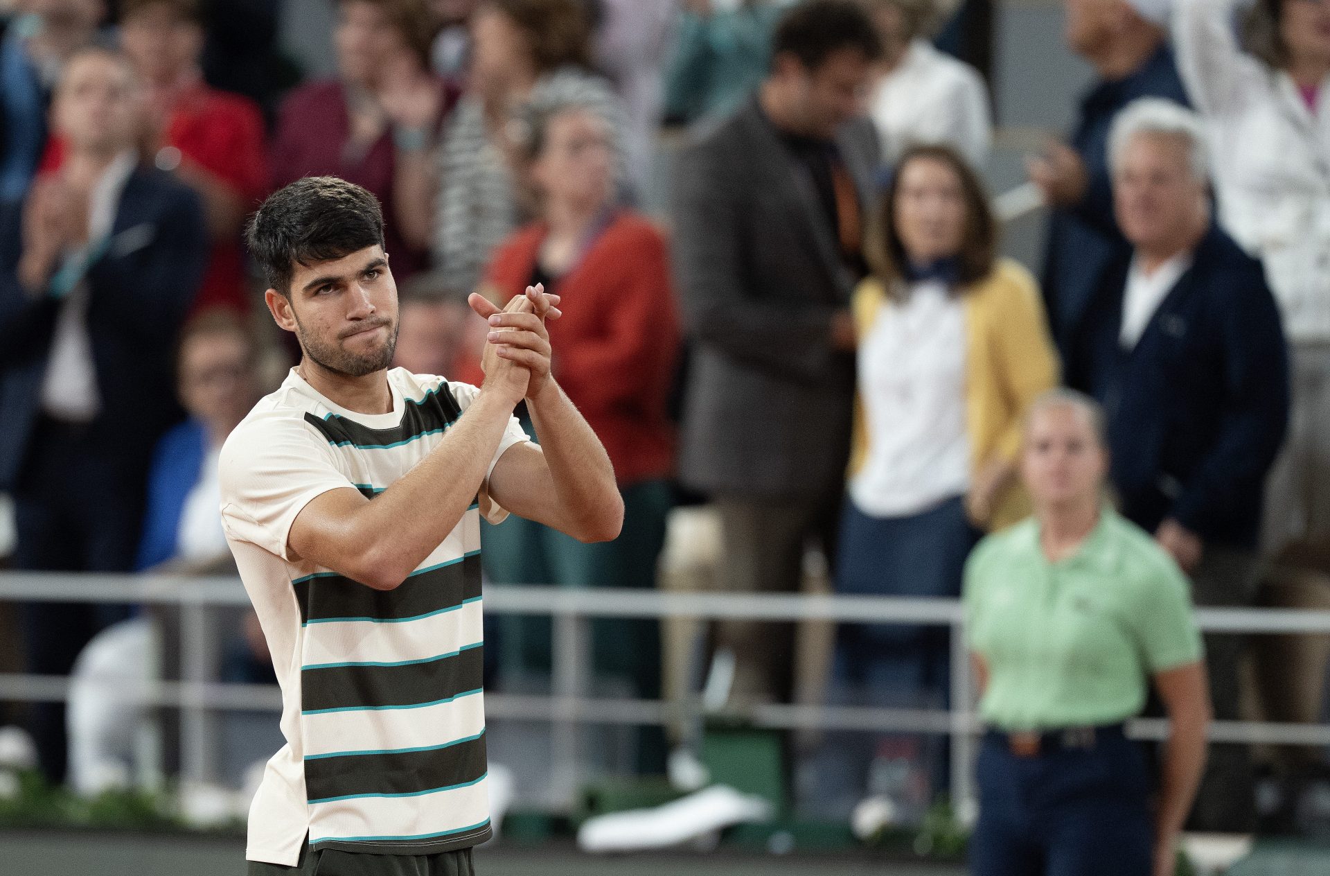 Carlos Alcaraz of Spain gives  Lorenzo Musetti of Italy a hand after Musetti retired in the fourth set of their match on day 13 at Roland Garros Stadium.