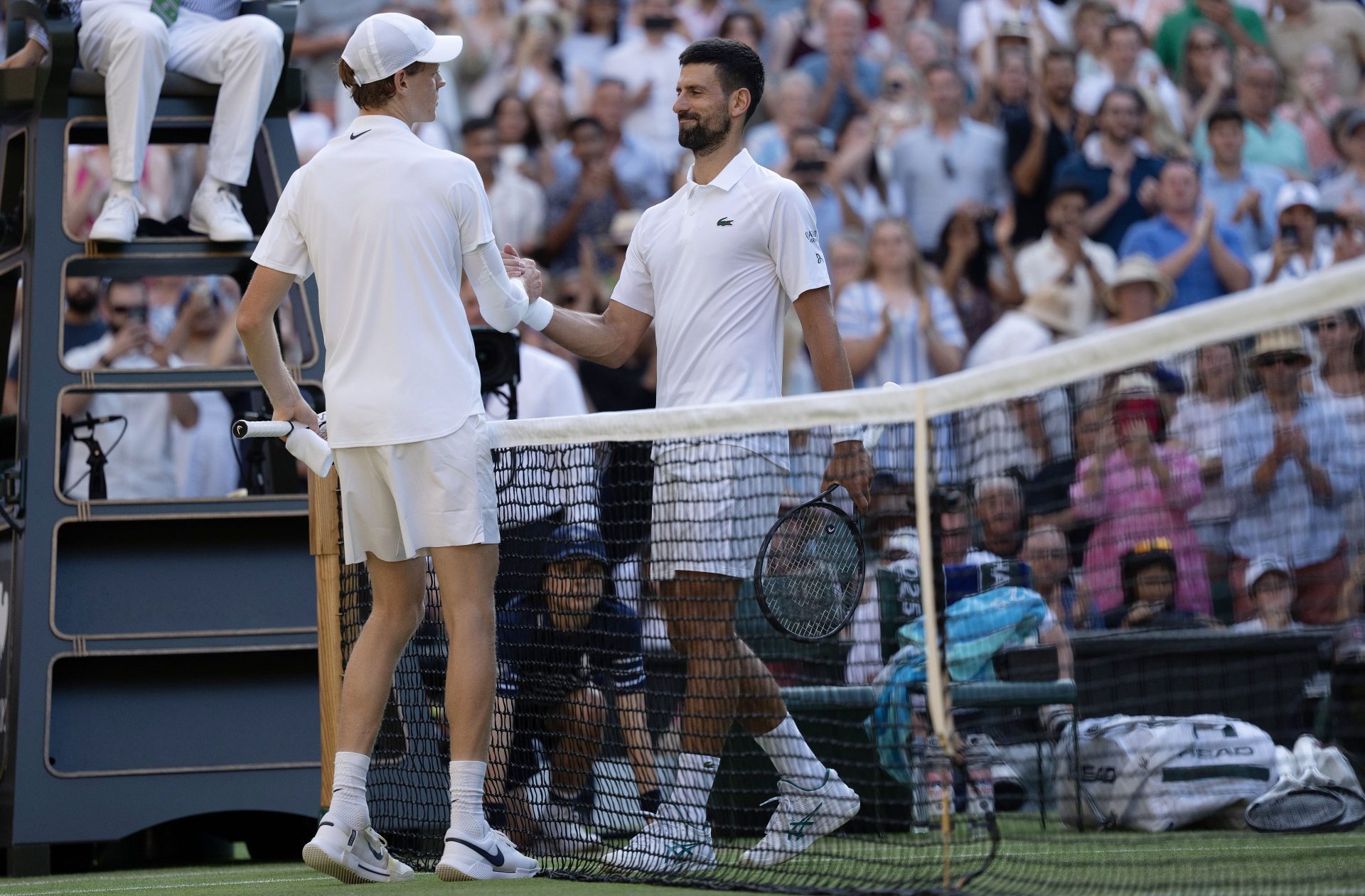 Jannik Sinner of Italy at the net with Novak Djokovic of Serbia after their match on day 12 at All England Lawn Tennis and Croquet Club.