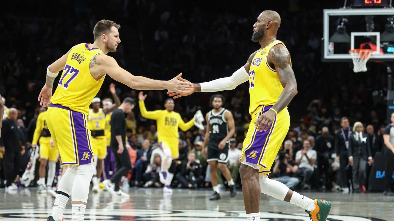 Los Angeles Lakers guard Luka Doncic (77) greets forward LeBron James (23) during a timeout in the first quarter against the Brooklyn Nets - Source: Imagn Images
